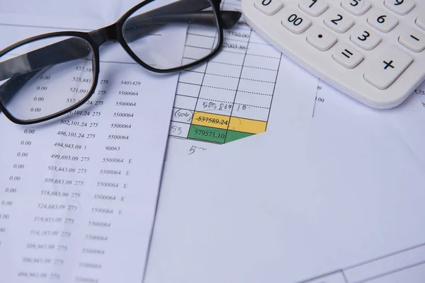 closeup accounts number on a printed paper ,Calculator and glasses.