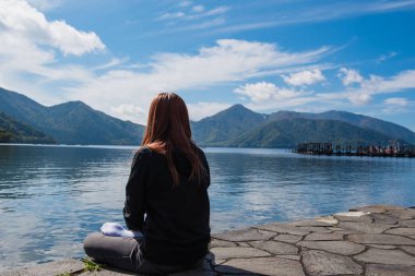 Yalnız göl ve mavi gökyüzü arka plan oturan kadın