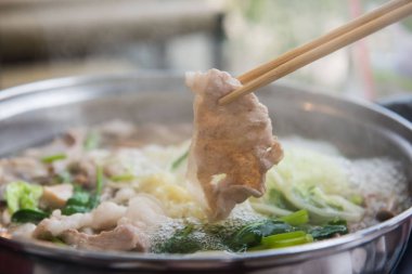 Shabu Shabu veya Sukiyaki veya güveç, domuz restoranında Japon yemekleri yemek çubukları, kullanarak tutan el 