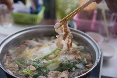 Shabu Shabu veya Sukiyaki veya güveç, domuz restoranında Japon yemekleri yemek çubukları, kullanarak tutan el 