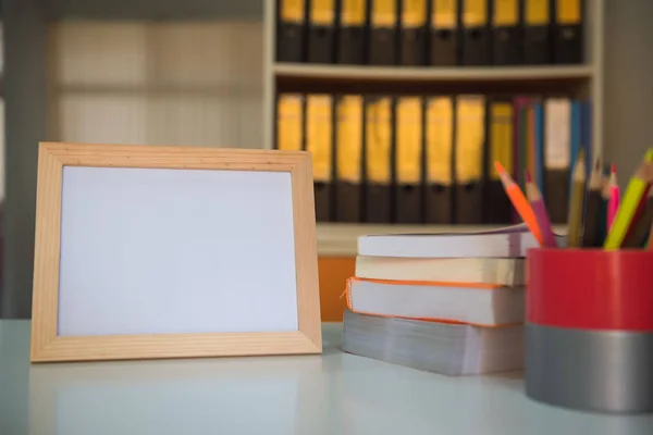 Фото Рамка и книга и цветные карандаши на столе в библиотеке  . — стоковое фото