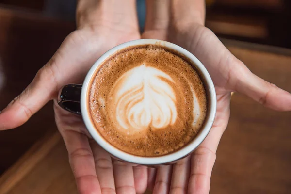 Wanita memegang secangkir kopi panas di tangan di kedai kopi — Stok Foto