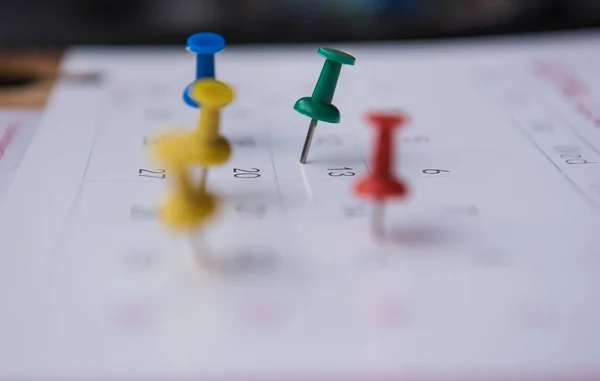 Närbild färgglada pins push märkning på en kalender. fullspäckade schema — Stockfoto