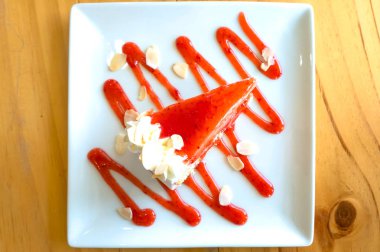 Masada beyaz tabakta çilekli cheesecake  .