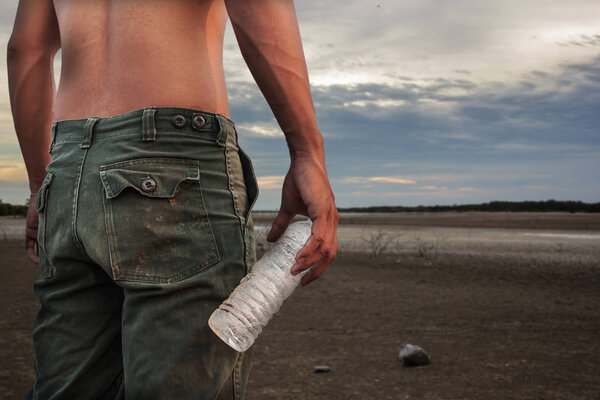 Man holding a bottle of water land to the ground dry cracked