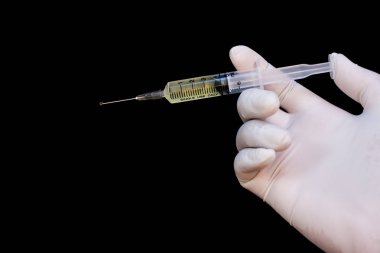 Ellerinde tıbbi eldiven olan şırınga, ilaç iğnesi için hazır. Siyah arkaplan