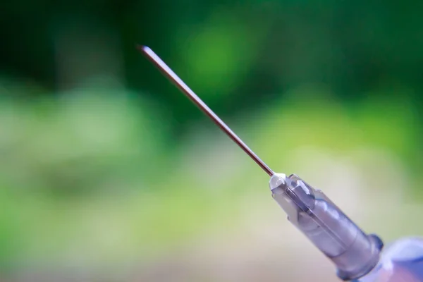 Seringa com agulha sobre fundo desfocado — Fotografia de Stock