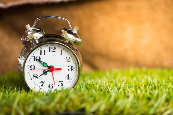 Reloj despertador por la mañana en la hierba — Foto de Stock