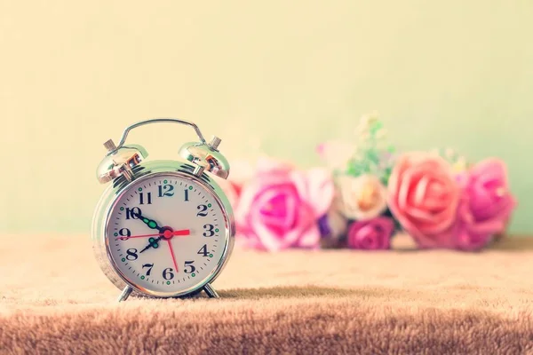 Pequeño reloj despertador con hermosas flores en la mesa estilo vintage —  Fotos de Stock