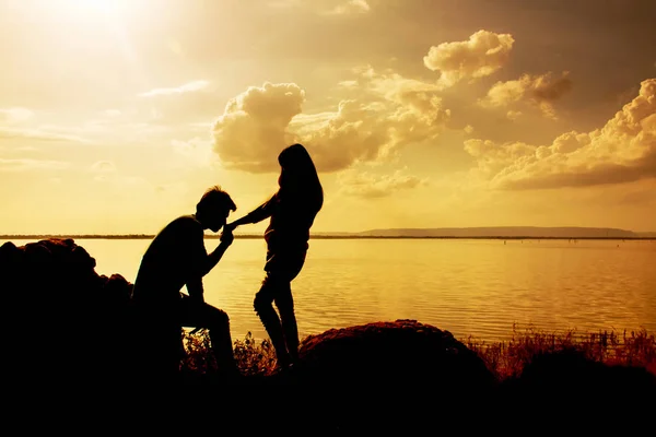 Silhuetter av mann og kvinne som kysser hånd ved solnedgang – stockfoto