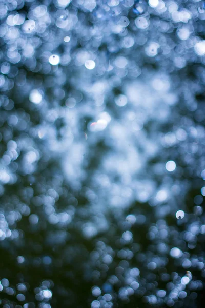 Bokeh sfocato di luci di Natale. Vacanza magica sfondo glitter astratto con stelle lampeggianti e fiocchi di neve che cadono . — Foto Stock