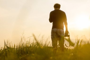 Genç adam günbatımında arıyor. Gezgin ile fotoğraf makinesi