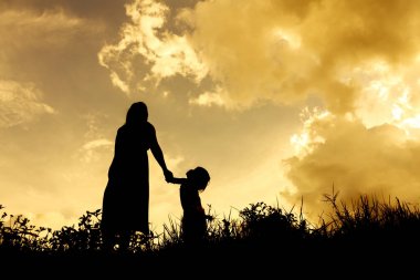 gün batımı sırasında çocuğu olan bir kadın siluetleri
