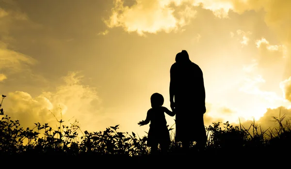 Silhuetas de uma mulher com seu filho durante o pôr do sol — Fotografia de Stock