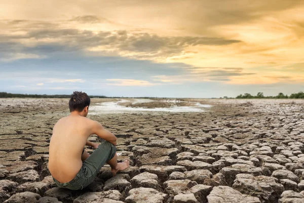 Crisis del agua, el hombre se sienta en tierra agrietada cerca del agua de secado . — Foto de Stock