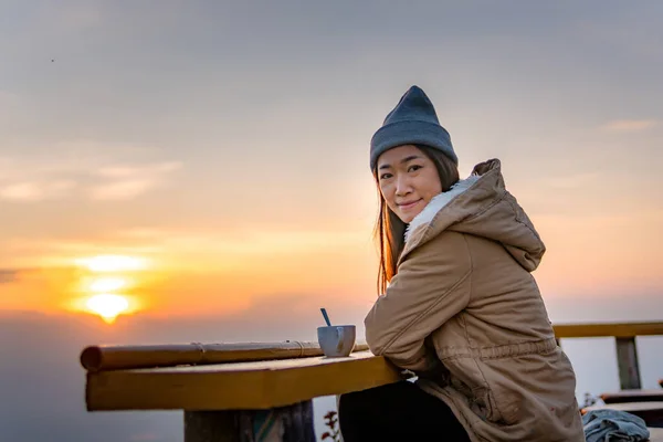 Uma mulher asiática senta café ao nascer do sol no topo de uma montanha . — Fotografia de Stock