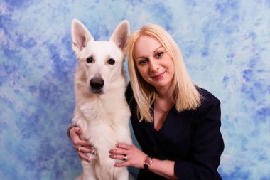 Güzel genç kadın ile mavi zemin üzerine beyaz köpek