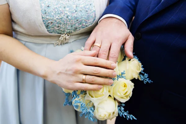 Руки жениха и невесты с кольцами и свадебным букетом — стоковое фото