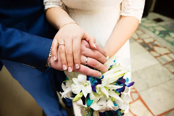 Mani dello sposo e della sposa con anelli e bouquet da sposa — Foto Stock