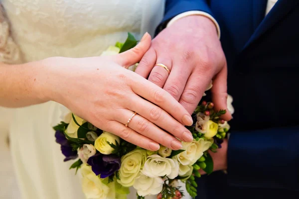 Τα χέρια του γαμπρού και της νύφης με δακτυλίους και νυφική ανθοδέσμη — Φωτογραφία Αρχείου