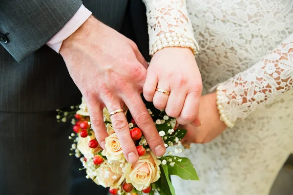 Mãos com anéis de casamento e buquê de noiva — Fotografia de Stock