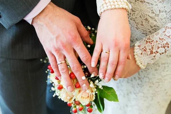 Mãos com anéis de casamento e buquê de noiva — Fotografia de Stock