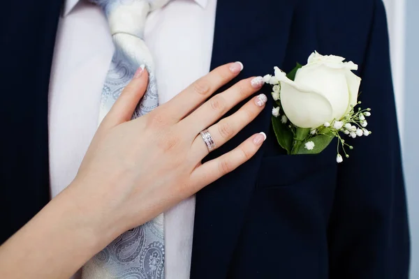 Boutonniere nuziale su abito di sposo e sposa mano — Foto Stock