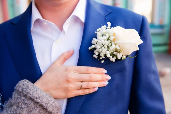 Casamento boutonniere em terno de noivo e noivas mão — Fotografia de Stock