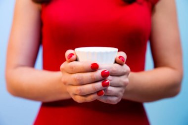 Kırmızı manikür ile kadının elinde çay