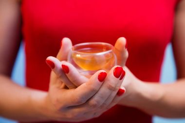 Kırmızı manikür ile kadının elinde çay