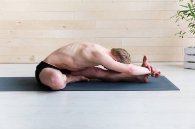 Paschimottasana poz yoga sınıfına yapan sportif erkek