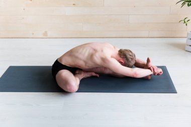 Paschimottasana poz yoga sınıfına yapan sportif erkek