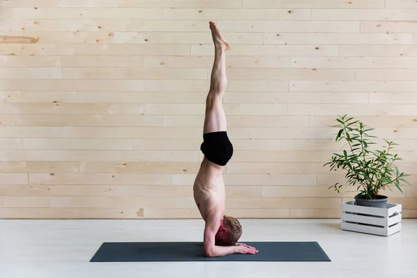 Sporty man practicing yoga.  Head stand, sirsasana exercise