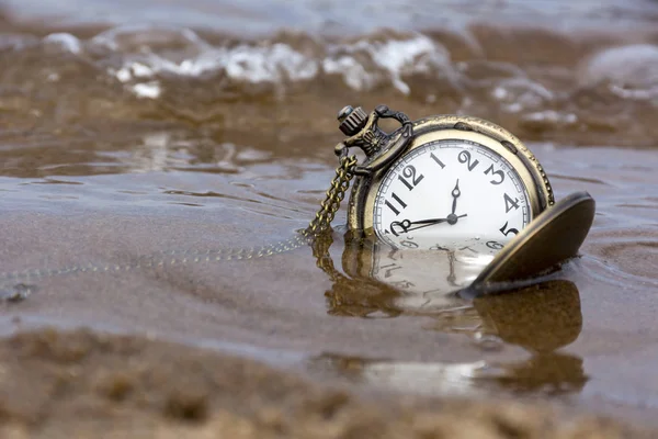 水の下で砂の上の機械式懐中時計のラウンド — ストック写真