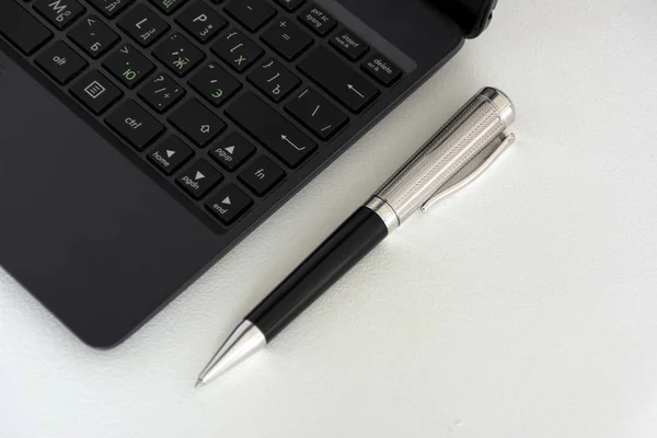 Penna a punta in metallo, tastiera nera su un tavolo — Foto Stock
