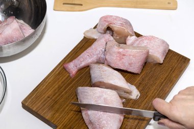 kadın bir levrek balık parçalar koparıp, keser