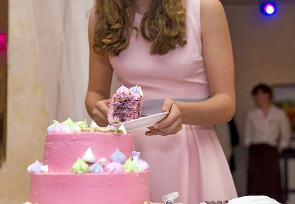 Κορίτσι βάζει ένα κομμάτι του κέικ σε πιάτο, το κορίτσι σε ένα ροζ φόρεμα, ένα κέικ — Φωτογραφία Αρχείου