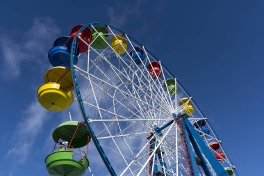 Dönme dolap ile güneş ve mavi gökyüzü arka plan üzerinde Renkli kabin