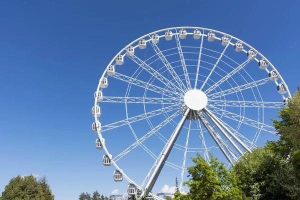 Weißes Riesenrad aus Metall mit Kabinen vor blauem Himmel, — Stockfoto