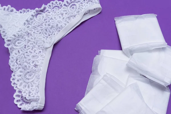 1 damskie białe koronki majtki, podkładki higieniczne na fioletowym tle — Zdjęcie stockowe