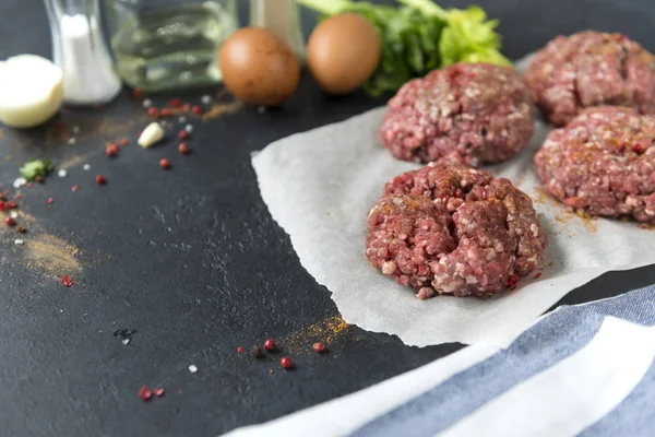 Hambúrgueres de porco crus em um fundo preto, costeletas de carne — Fotografia de Stock