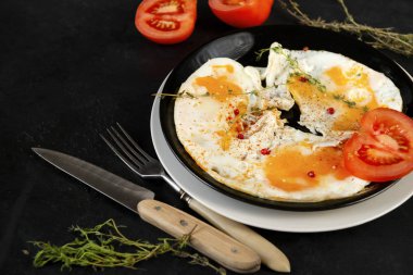 Çırpılmış yumurta, kekik ve domatesli siyah bir sırt çanağı.