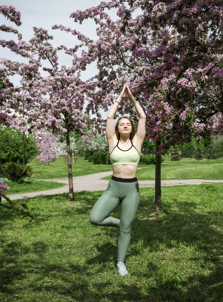 1 junge Frau in Sportkleidung steht in einem Baum in einer blühenden Pose — Stockfoto
