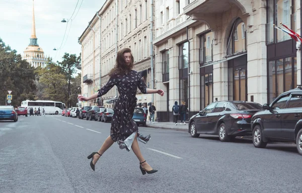 Femeia într-o rochie lungă aleargă peste stradă în oraș împotriva — Fotografie, imagine de stoc