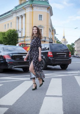 white young woman in a long dress walking on a road in the city 