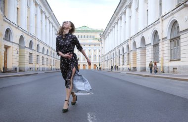1 young woman in a brown dress walks down the street against the