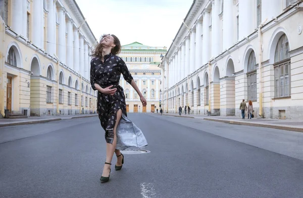 1 молодая женщина в коричневом платье идет по улице против — стоковое фото