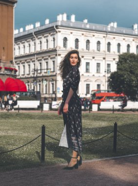 white young woman in a long dress in the city on the background 