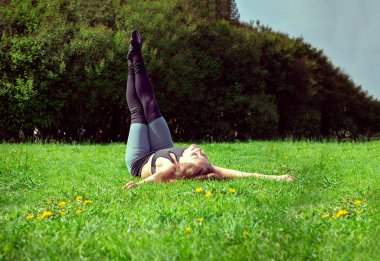 1 white young woman in leggings lying on the green grass in the 