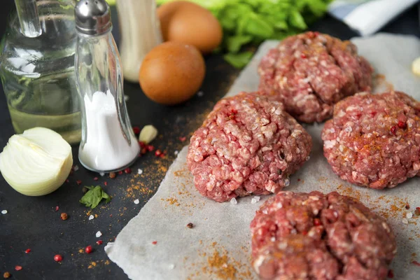 Hambúrgueres de carne, costeletas redondas de porco com temperos em um backgrou preto — Fotografia de Stock